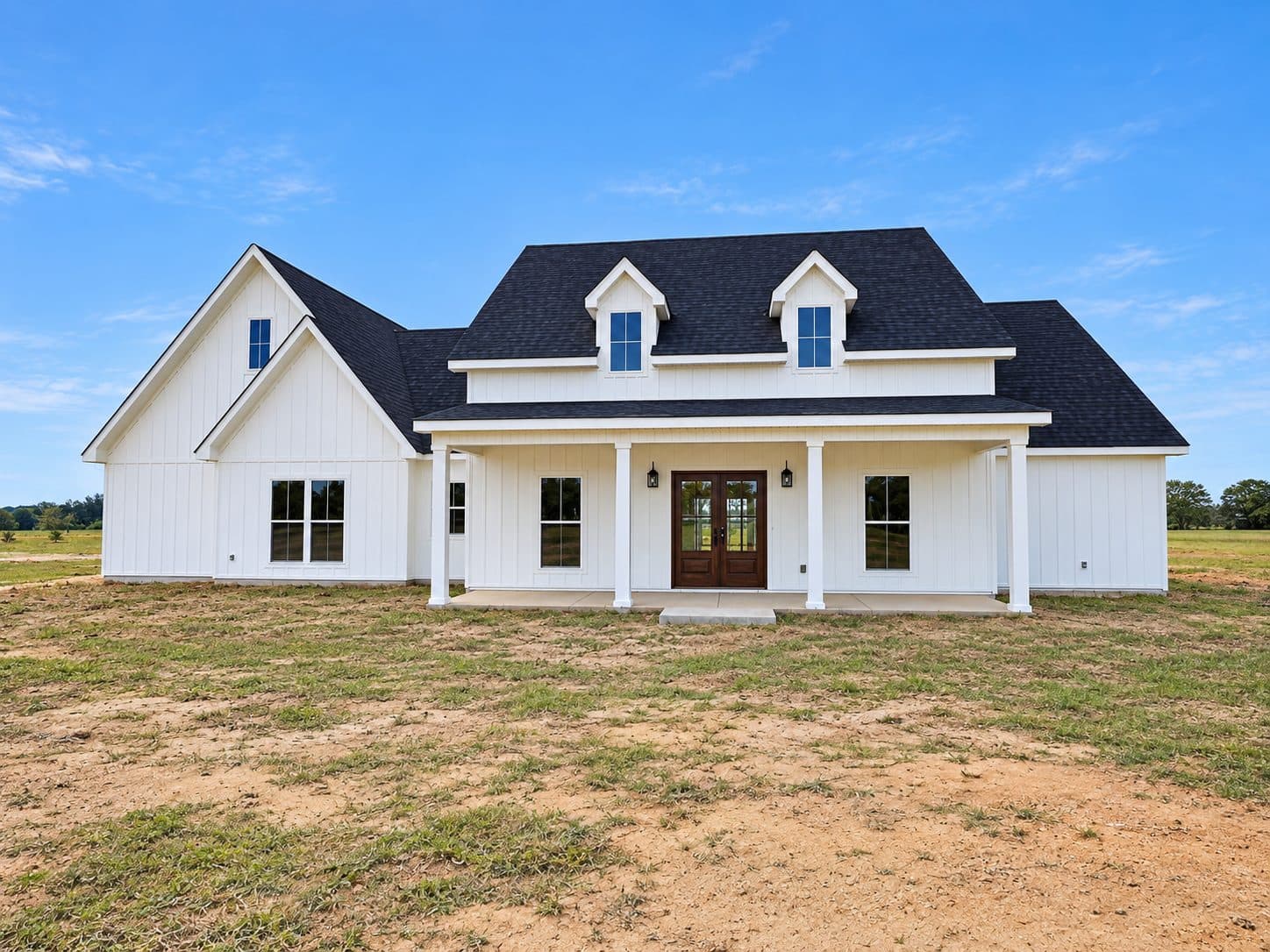 White Farmhouse with board-and-batten siding, dormers and a covered front porch